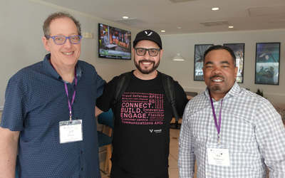 Three attendees wearing name badges, posing together