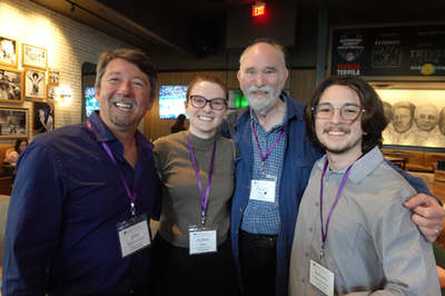 Four attendees with name badges, posing together