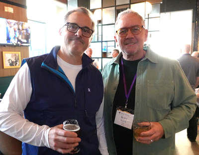 Two attendees holding drinks, posing together