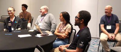 Attendees seated around a table with laptops