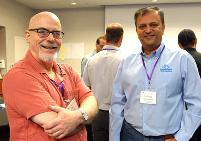 Two attendees posing, with others talking behind them